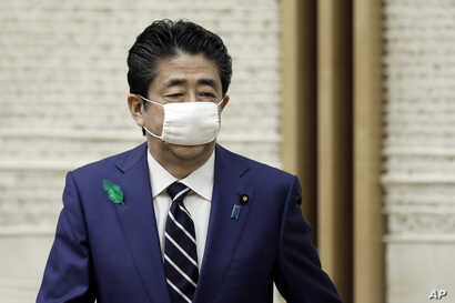 Wearing a protective mask, Japanese Prime Minister Shinzo Abe leaves a news conference at the prime minister's official…