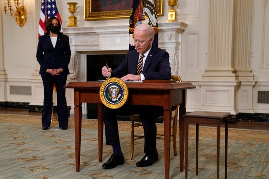 President Joe Biden signs an executive order relating to U.S. supply chains, in the State Dining Room of the White House, Wednesday, Feb. 24, 2021, in Washington, as Vice President Kamala Harris watches.