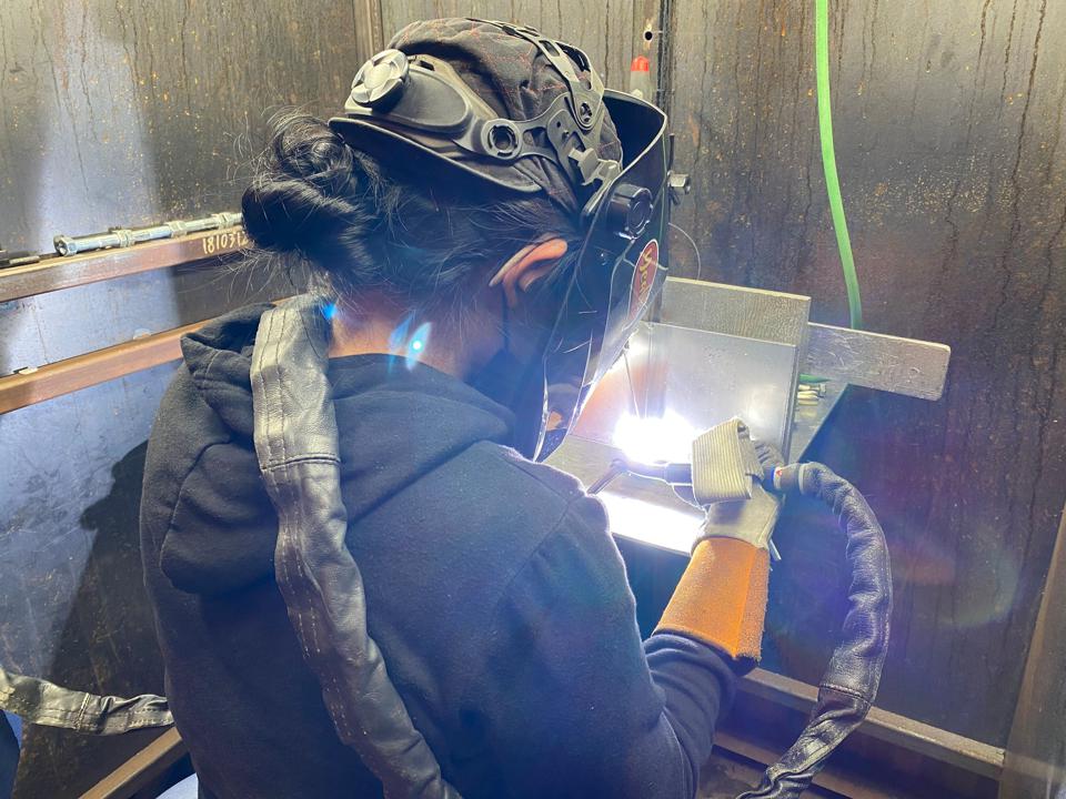 A female veteran receives hands-on welding training.