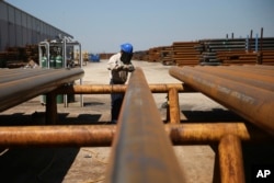 FILE - Jose Mata grinds a steel pipe at the Borusan Mannesmann plant in Baytown, Texas, April 23, 2018.