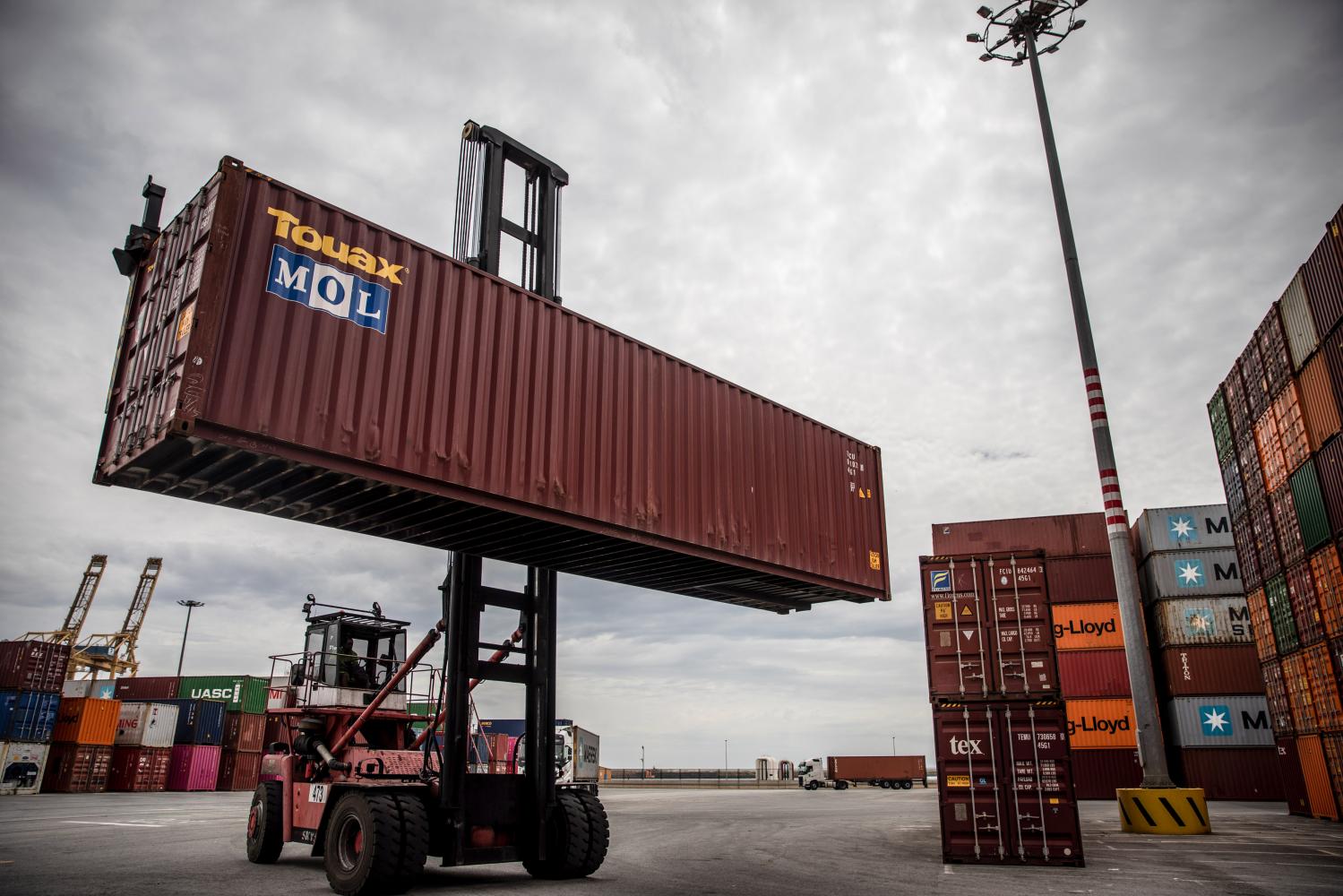 A reach stacker lifts a shipping container in Barcelona, Spain. Supply-chain stresses are exacerbating global inflation, threatening to further pressure global trade. (Photo: Bloomberg)